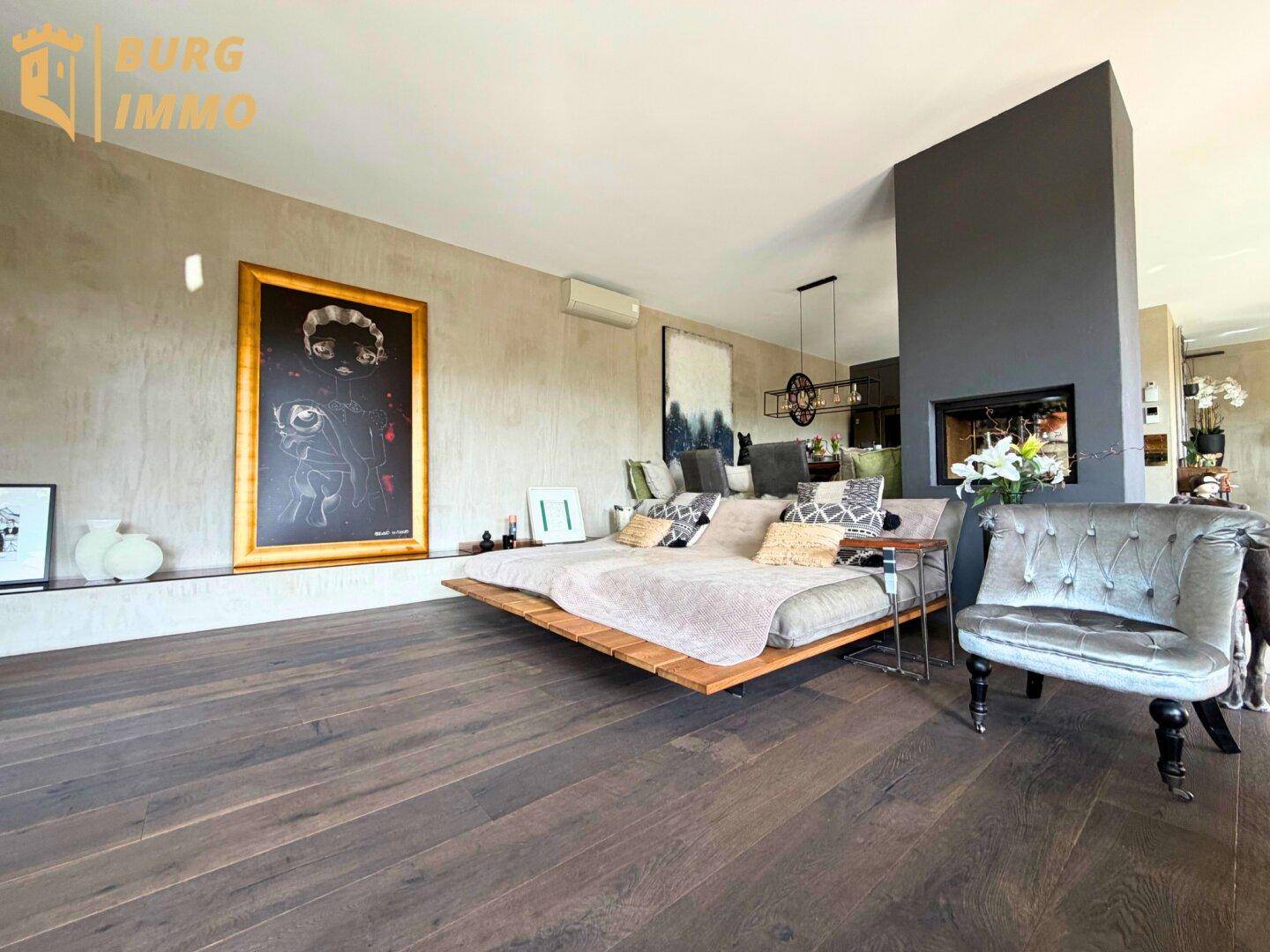 Geräumiges Wohnzimmer mit großem Sofa, Kamin und dunklem Holzboden, modern eingerichtet.