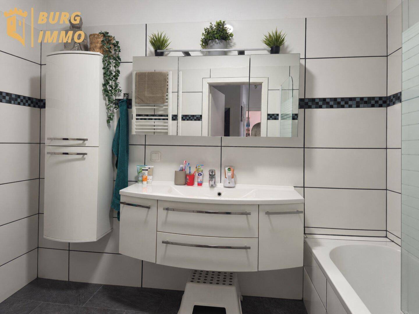 Helles Badezimmer mit modernem Waschtisch, Spiegelschrank und weißen Fliesen.