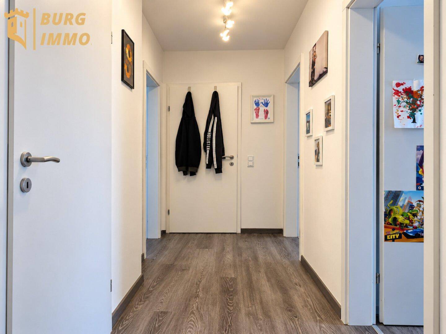 Heller Flur mit Laminatboden, Garderobe und Zugang zu verschiedenen Räumen.