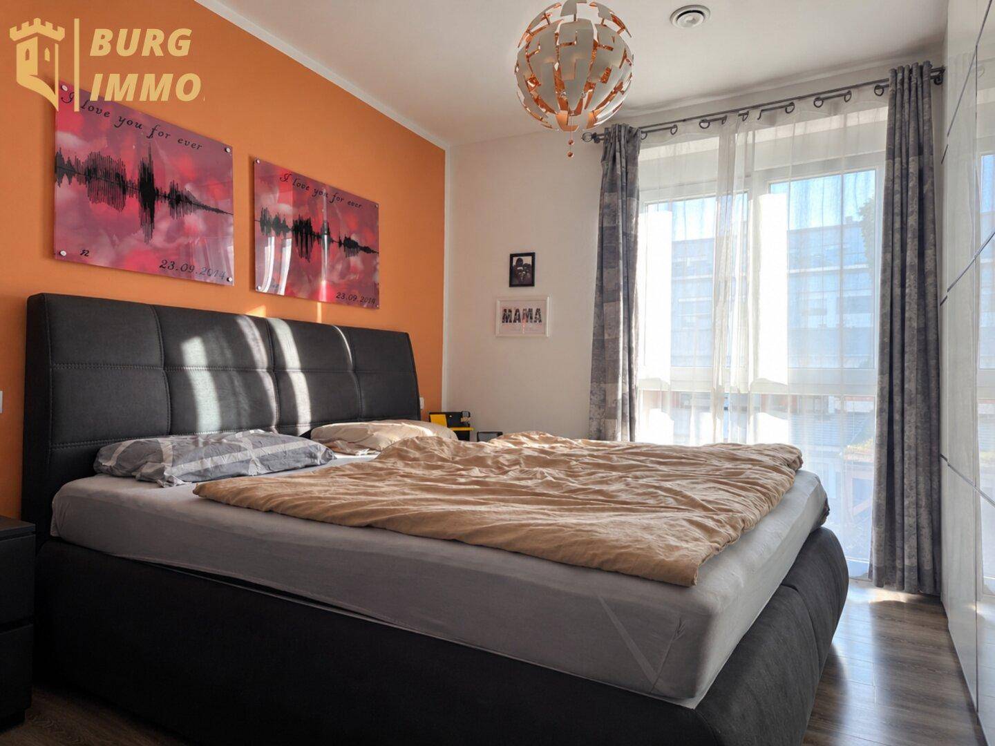 Modernes Schlafzimmer mit Doppelbett, orangefarbener Akzentwand und großem Fenster.