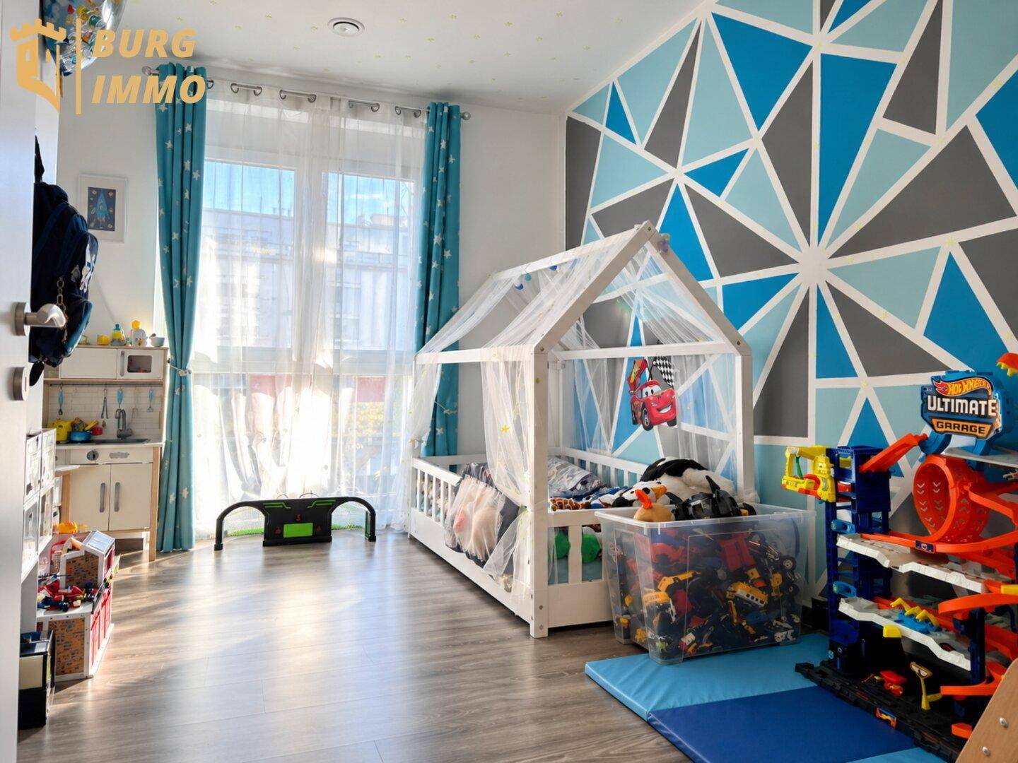 Farbenfrohes Kinderzimmer mit Spielzeug, Holzbett und geometrischer Wandgestaltung.