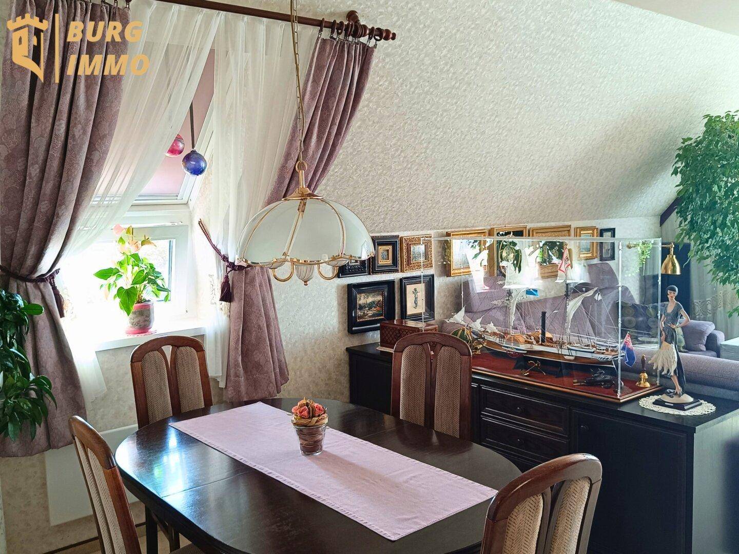 Gemütlicher Essbereich im Dachgeschoss mit klassischem Holztisch und Fenster.
