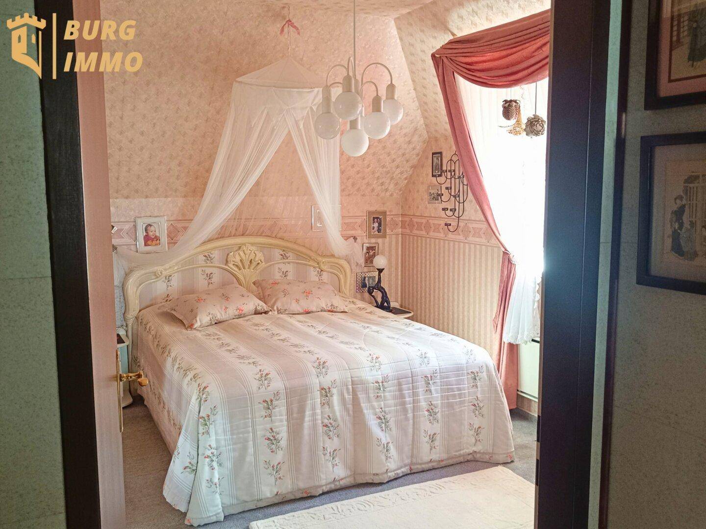 Romantisches Schlafzimmer im Dachgeschoss mit Himmelbett und floraler Tapete.