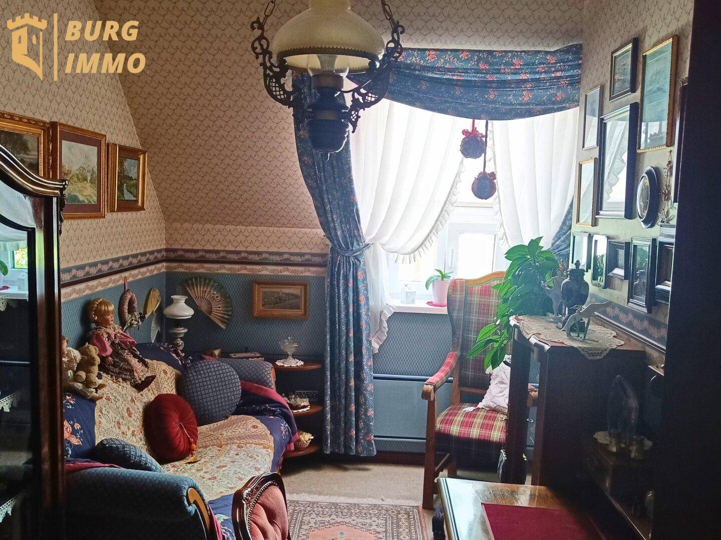 Detailreicher Wohnbereich im Dachgeschoss mit traditioneller Einrichtung und Fenster.