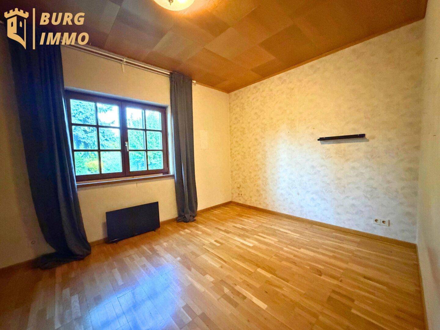 Schlafzimmer mit Holzboden, Holzdecke und großem Fenster mit Blick ins Grüne.