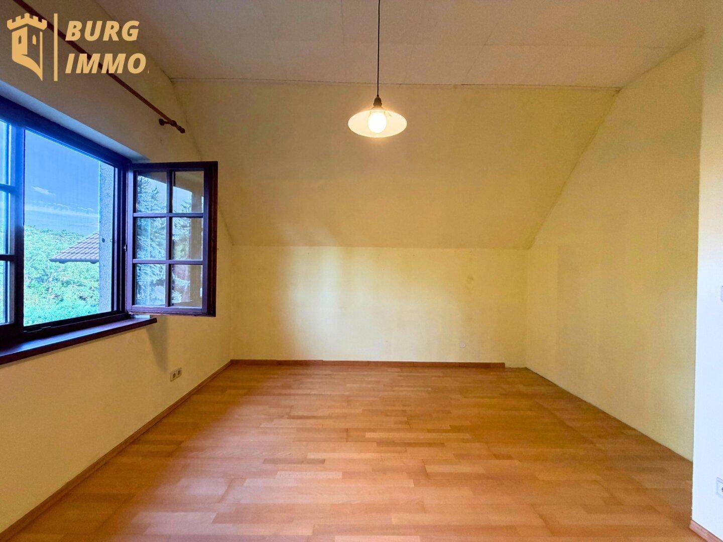 Heller Raum im Dachgeschoss mit Holzboden und schrägen Decken.