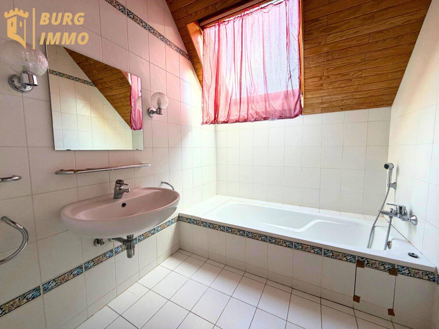Badezimmer im Dachgeschoss mit Badewanne, Waschbecken und Dachfenster.