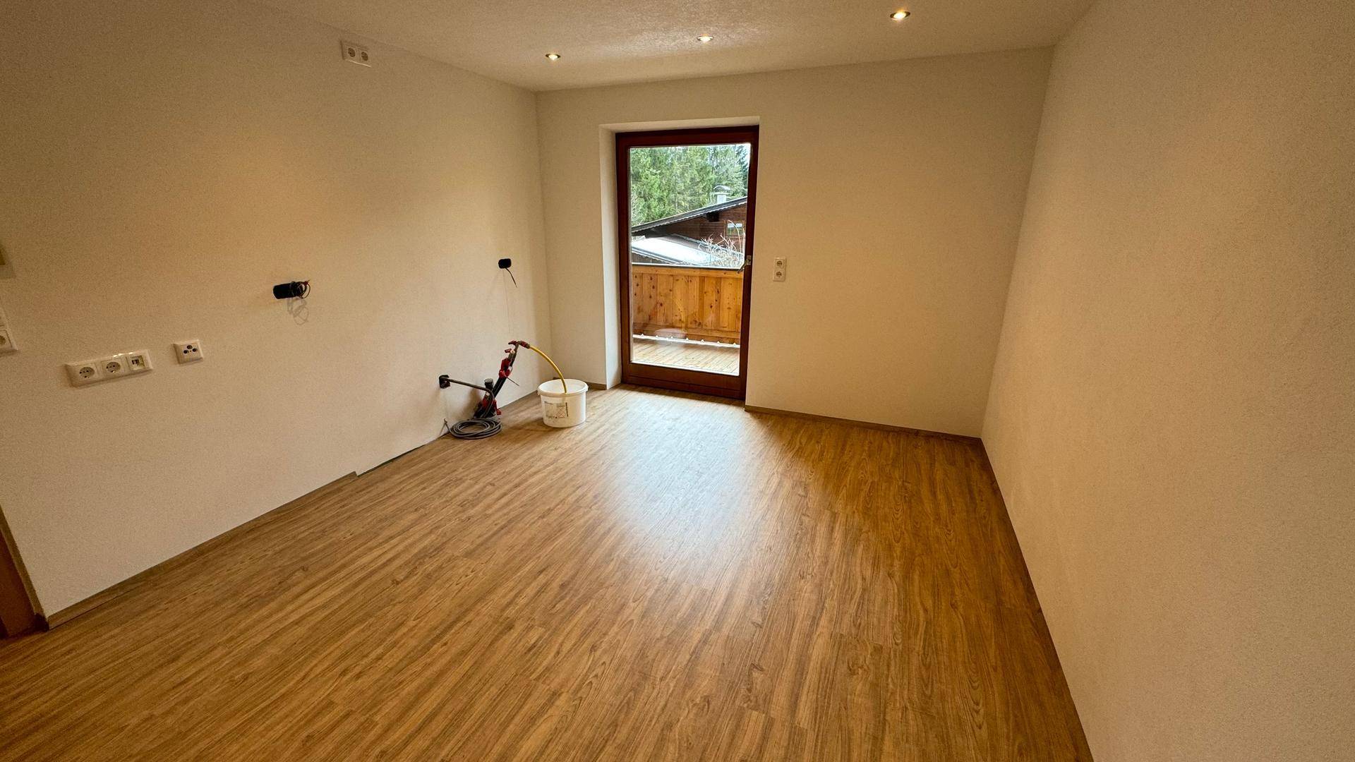 Unmöblierter Raum mit Laminatboden und Zugang zu einem Balkon, ideal für die zukünftige Nutzung als Wohn- oder Schlafzimmer.