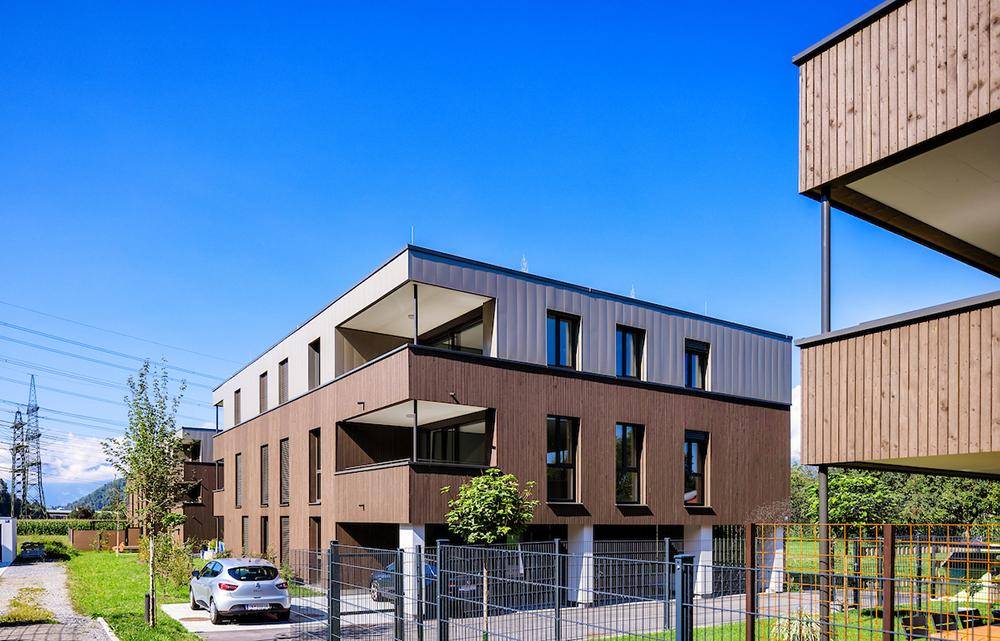 Modernes Wohngebäude mit Holzfassade, Balkonen und Außenparkplätzen.