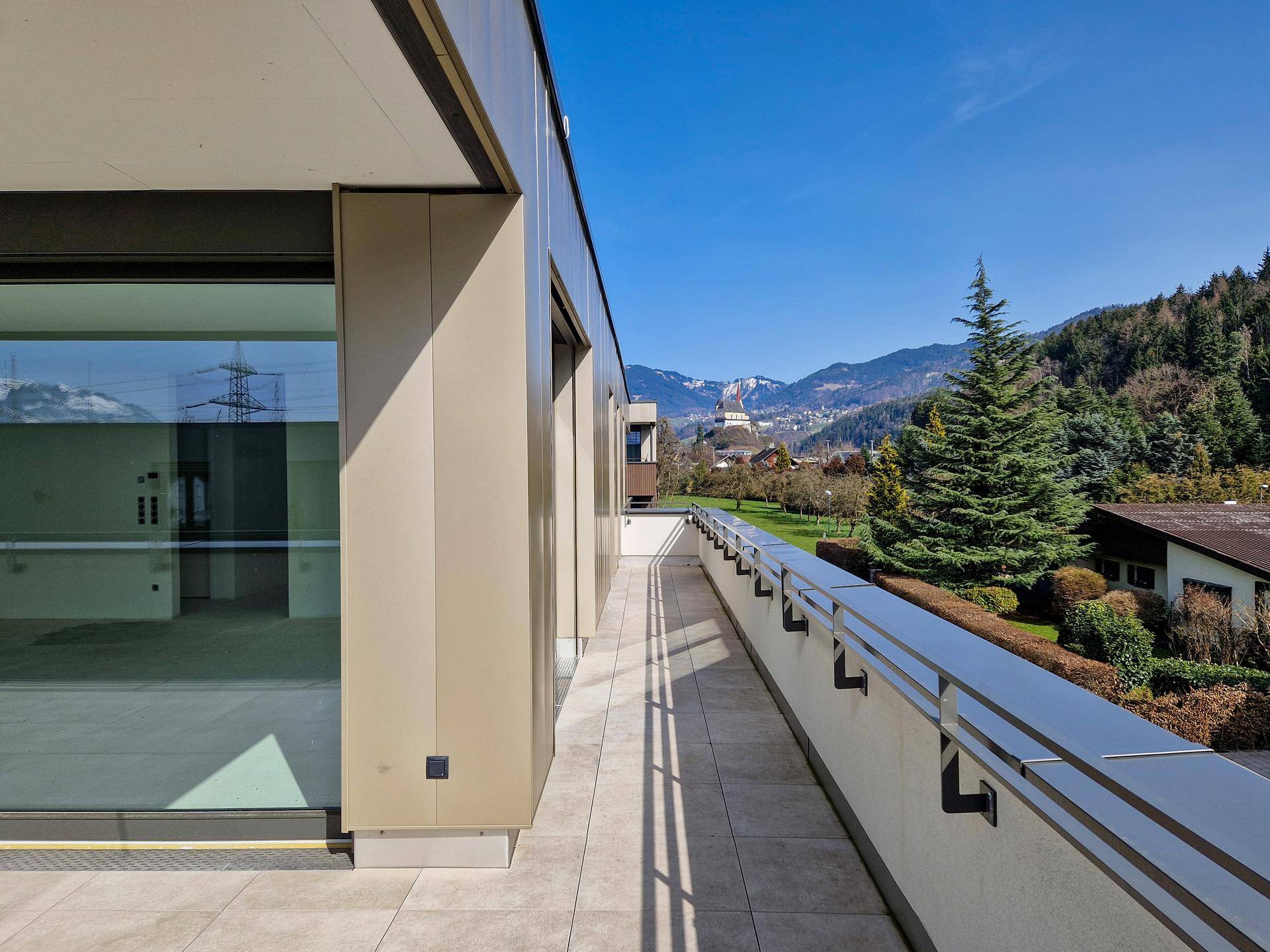 Langer Balkon mit Fliesenboden und Panoramablick auf die Berge und Wälder.