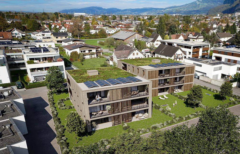 Luftaufnahme von modernen Wohngebäuden mit begrünten Dächern und Photovoltaikanlagen in ländlicher Umgebung.