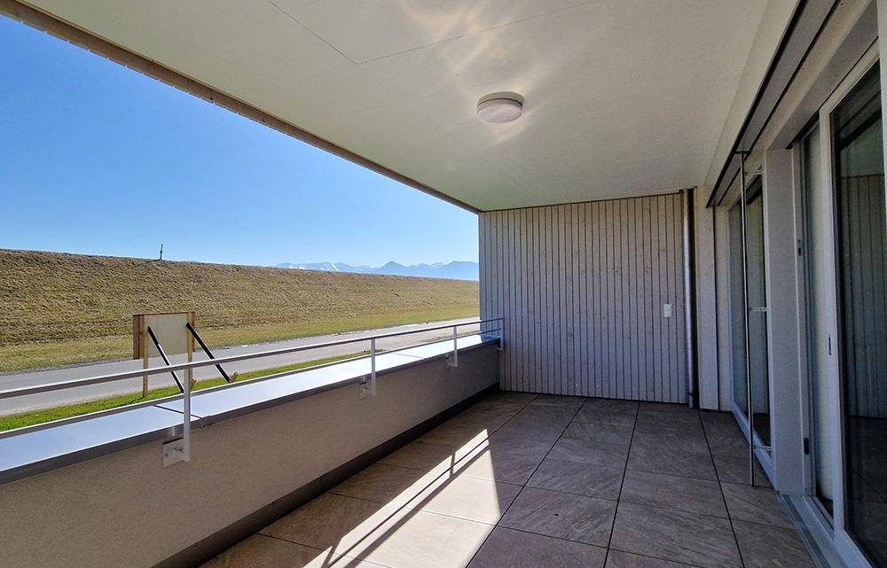 Geräumiger Balkon mit Fliesenboden und weitem Blick auf die Berge und die umliegende Landschaft.
