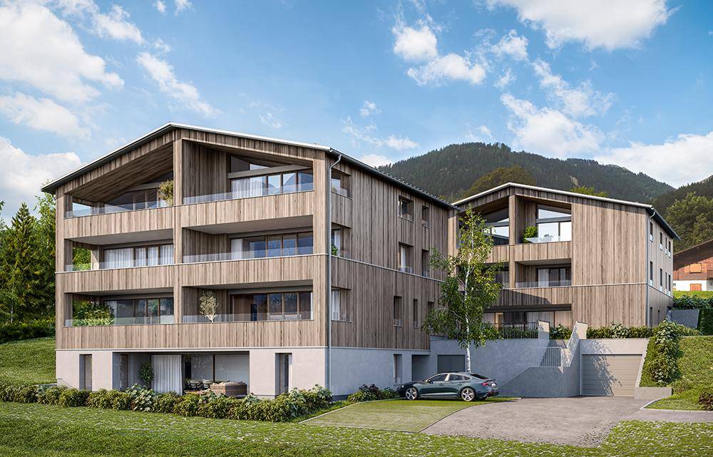 Moderne Mehrfamilienhäuser mit Holzfassade und großen Balkonen vor einer Bergkulisse.