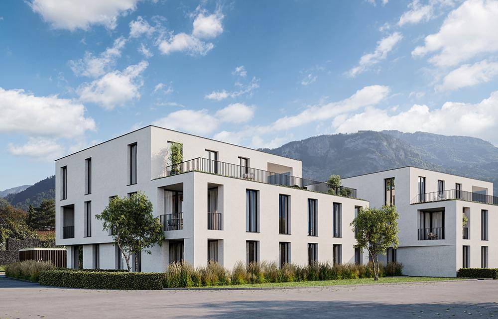 Neubau-Wohnkomplex mit moderner Architektur und Blick auf die umliegenden Berge.