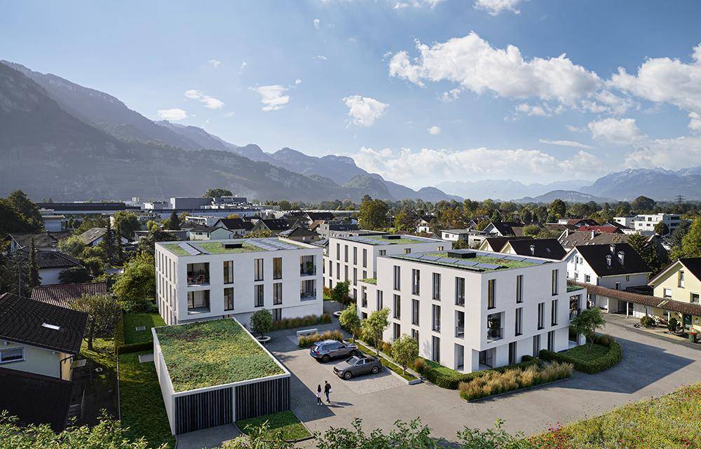 Luftaufnahme einer modernen Wohnsiedlung mit Flachdächern und Bergblick.