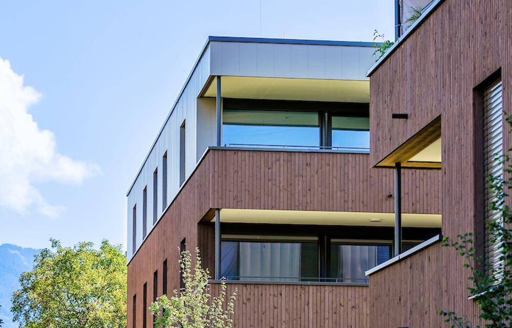 Detailansicht der modernen Holzfassade mit Balkonen und großen Fenstern.