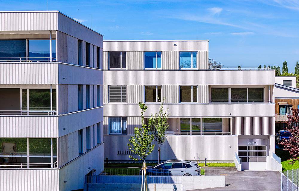 Detailansicht der modernen Wohngebäude mit Holzfassade und großen Fenstern.