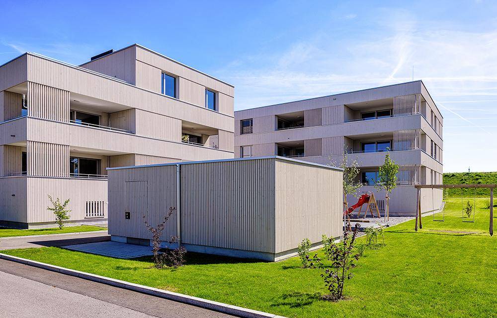 Moderne Wohngebäude mit Spielplatz und Grünflächen für Kinder im Freien.