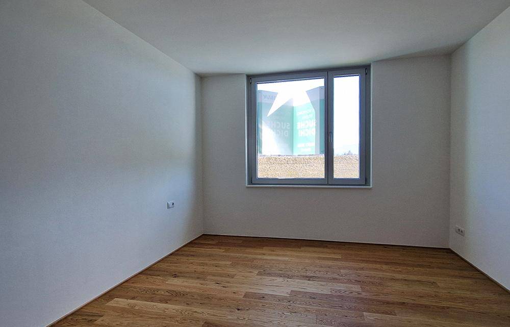 Leerer Raum mit Holzboden und einem Fenster, bereit zur individuellen Gestaltung.