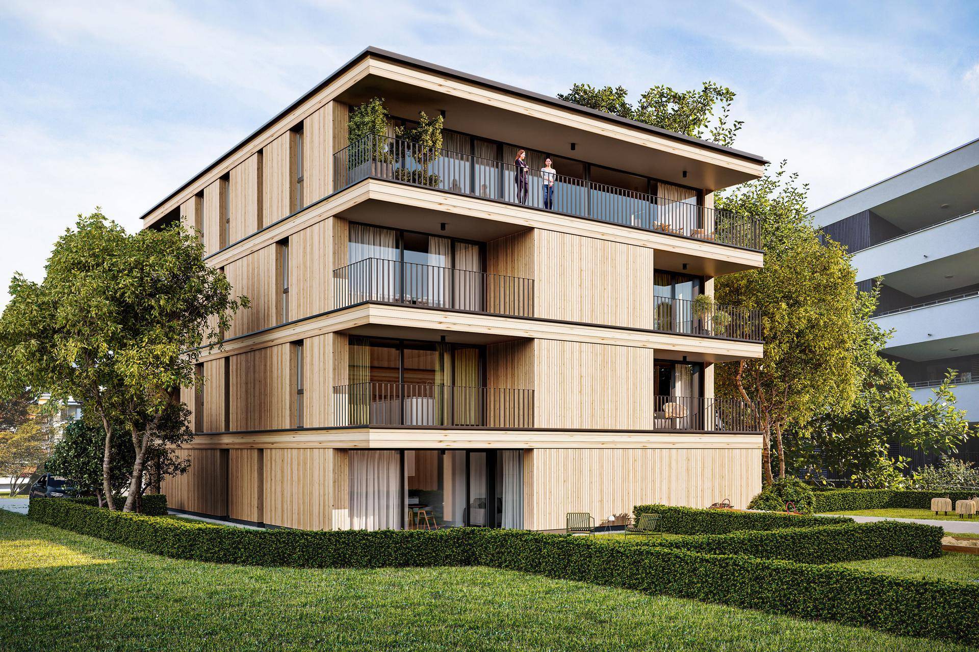 Modernes Wohnhaus mit Holzfassade, großzügigen Balkonen und umliegender Grünfläche.