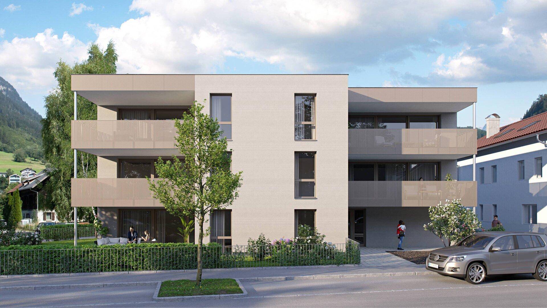 Moderne Wohnanlage mit Balkonen und Grünflächen in einer bergigen Umgebung.