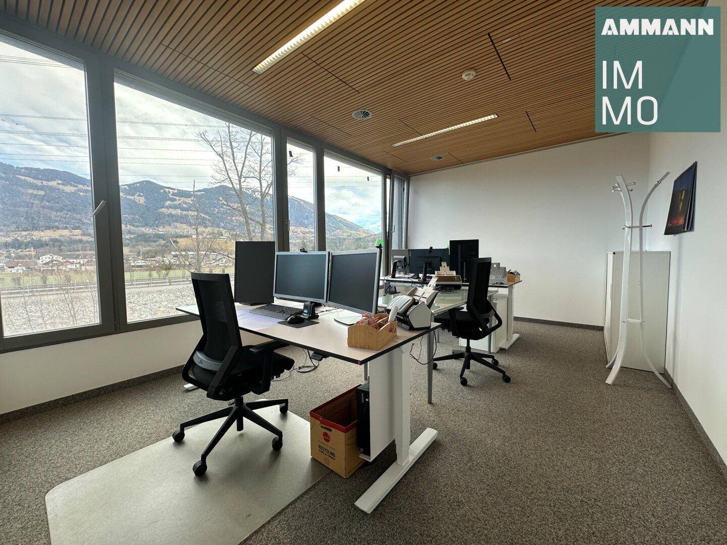 Arbeitsplatz mit Blick auf die Berge, großen Fenstern und höhenverstellbaren Schreibtischen.