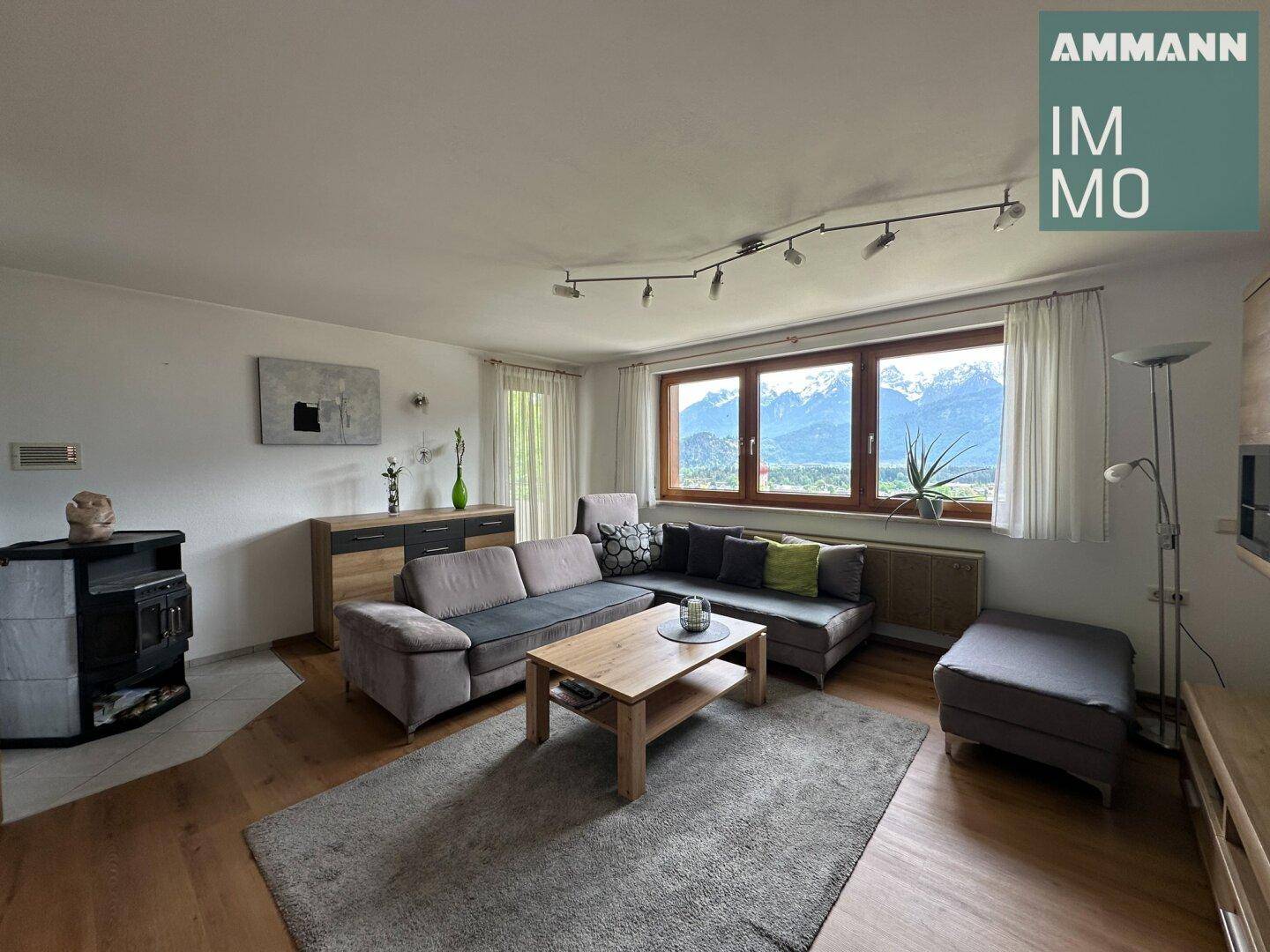 Helles Wohnzimmer mit Holzboden, gemütlicher Sitzecke und Kaminofen.