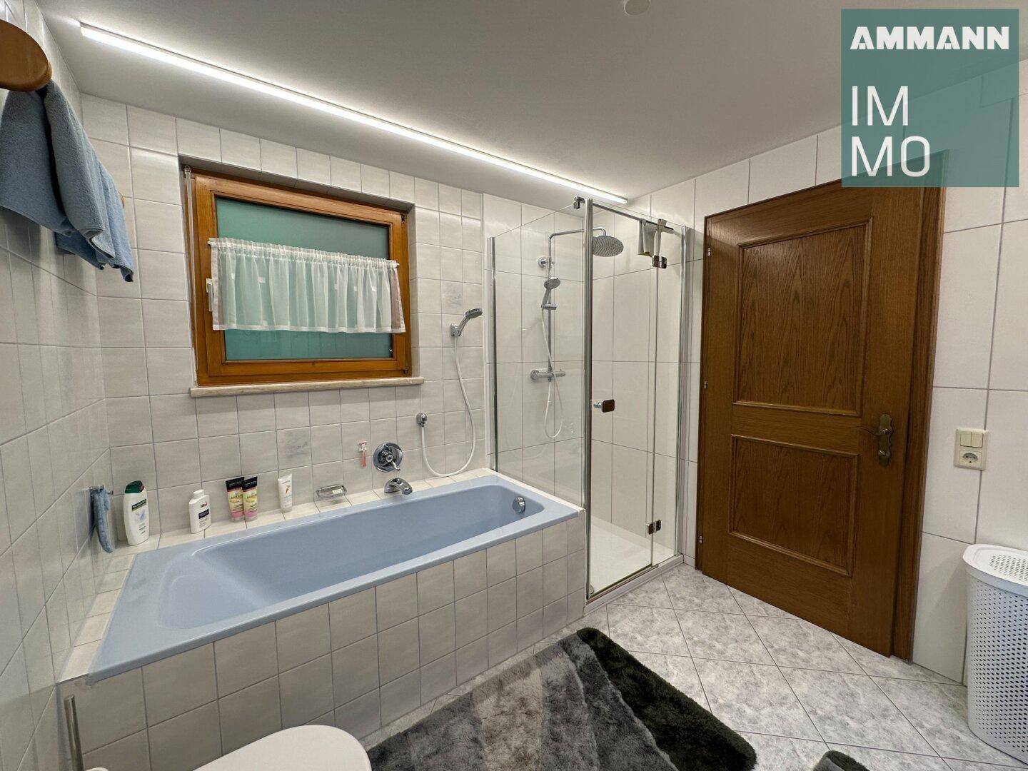Badezimmer mit Badewanne, separater Dusche und Fenster für Tageslicht.