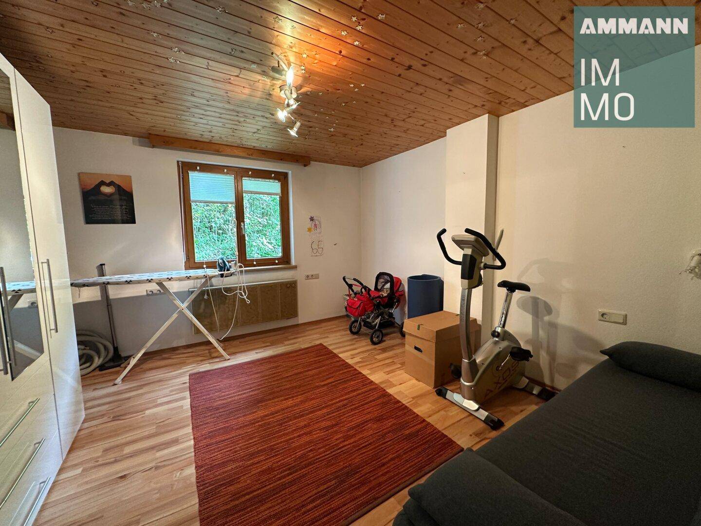 Vielseitig nutzbarer Raum mit Holzdecke, Laminatboden und Fenster zum Garten.