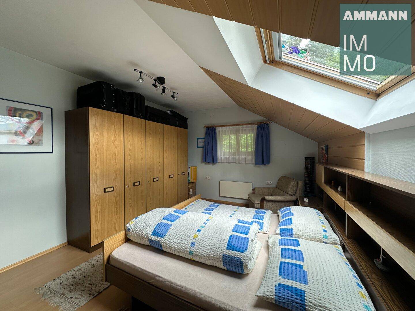 Dachgeschoss-Schlafzimmer mit Dachschräge, Einbauschränken und Dachfenster.