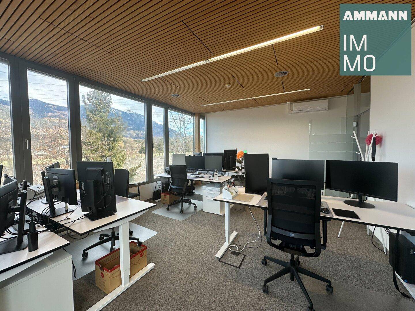 Helles und modernes Büro mit zahlreichen Arbeitsplätzen, Holzdecke und weitem Ausblick.