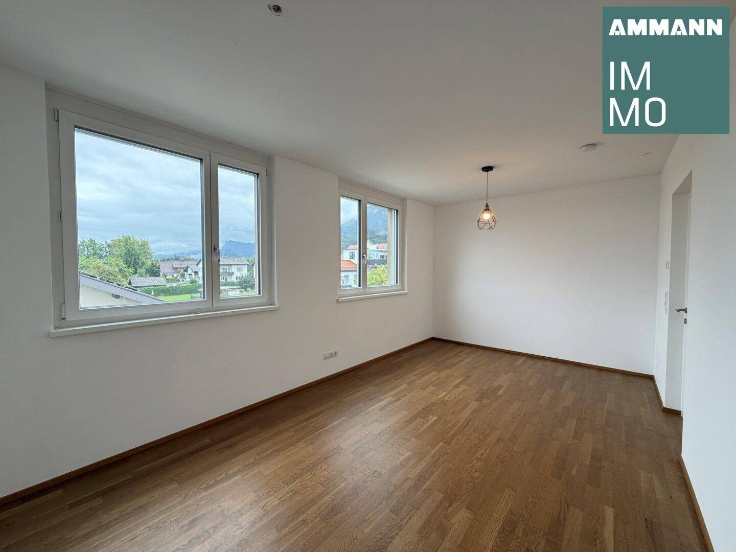 Lichtdurchflutetes Zimmer mit zwei Fenstern, Holzboden und Blick auf die Umgebung.
