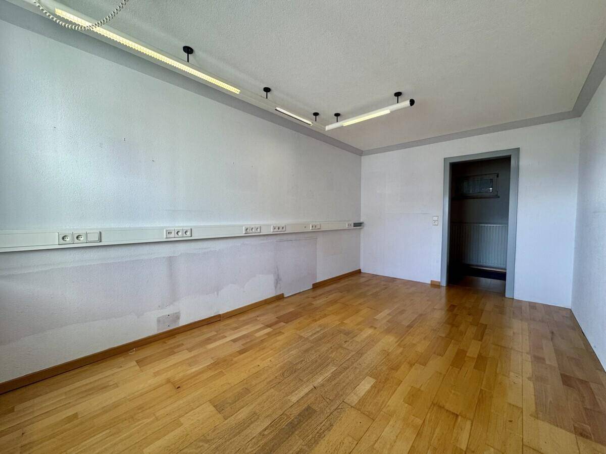 Geräumiger Raum mit Holzboden und vielen Steckdosen, ideal als Büro oder Hobbyraum.