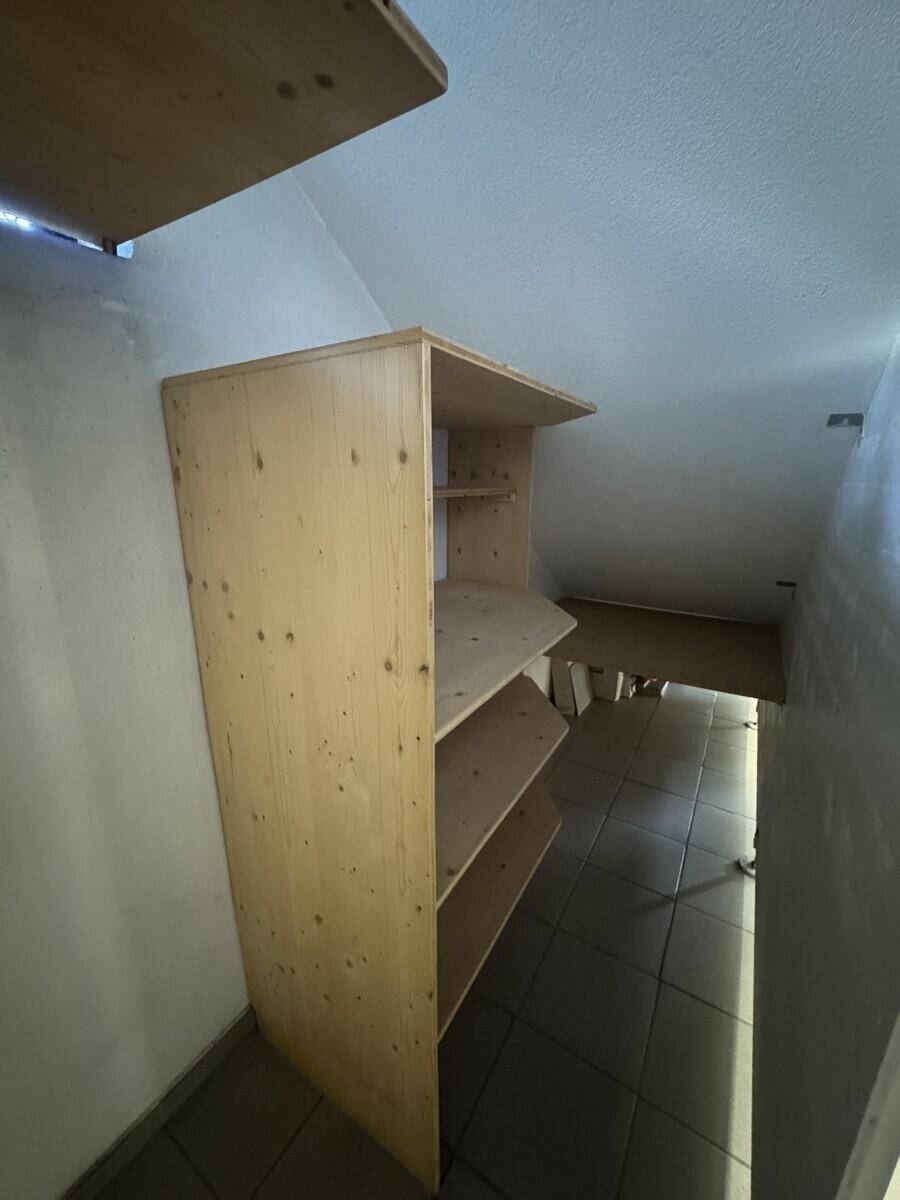Kleiner Abstellraum mit Holzregalen und gefliestem Boden, praktisch für Haushaltsgegenstände.