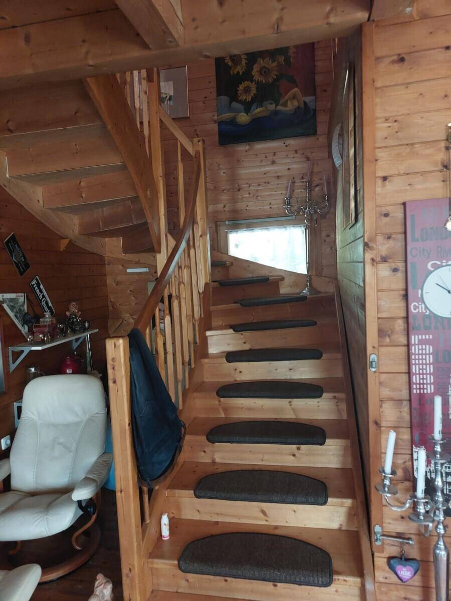 Rustikale Holztreppe mit Teppichstufen, die in das obere Stockwerk des Holzhauses führt.