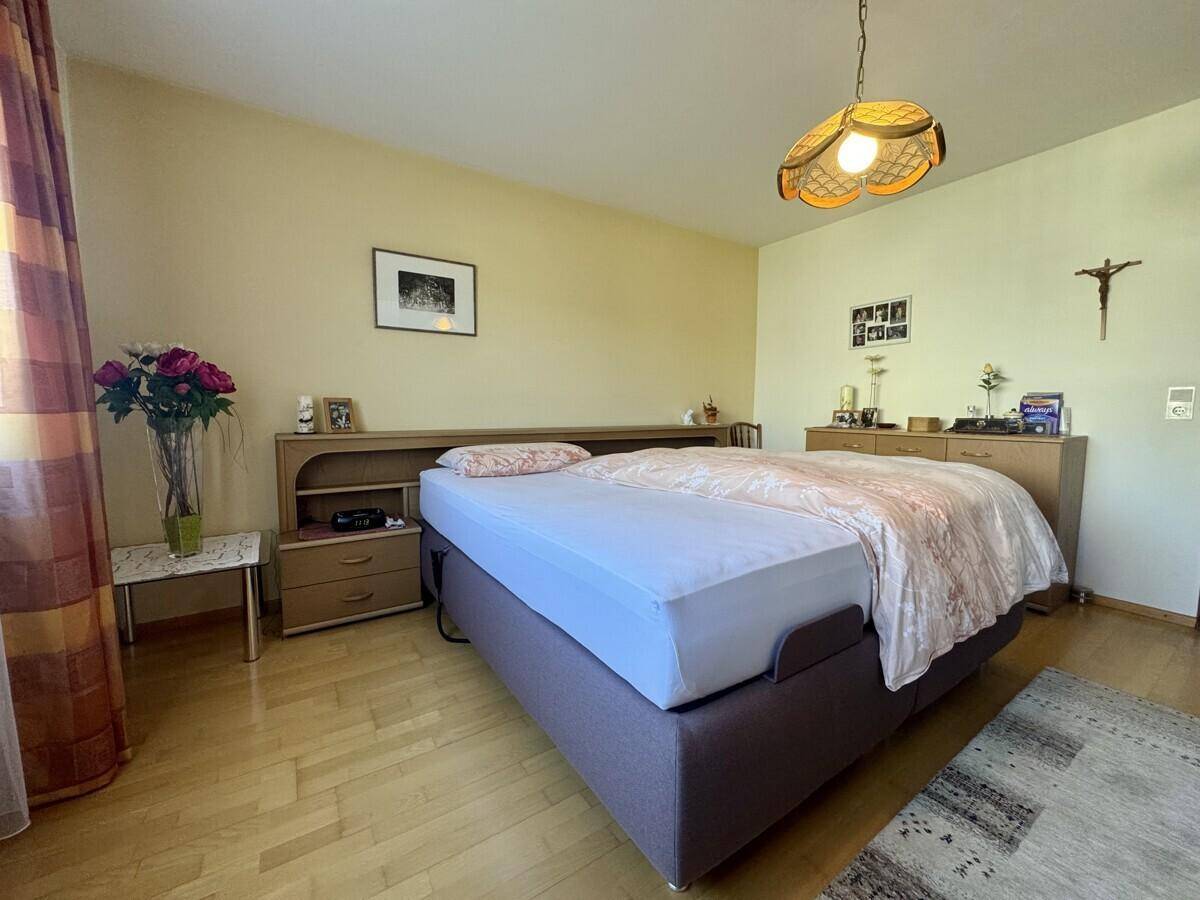 Schlafzimmer mit Doppelbett, Holzmöbeln und hellem Laminatboden.