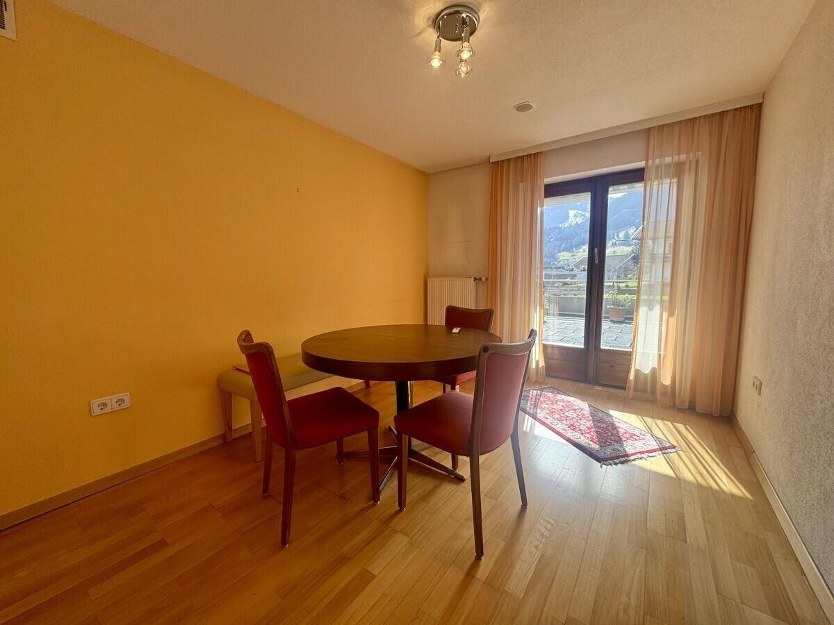 Esszimmer mit Holztisch und Stühlen, gelben Wänden und Zugang zur Terrasse.