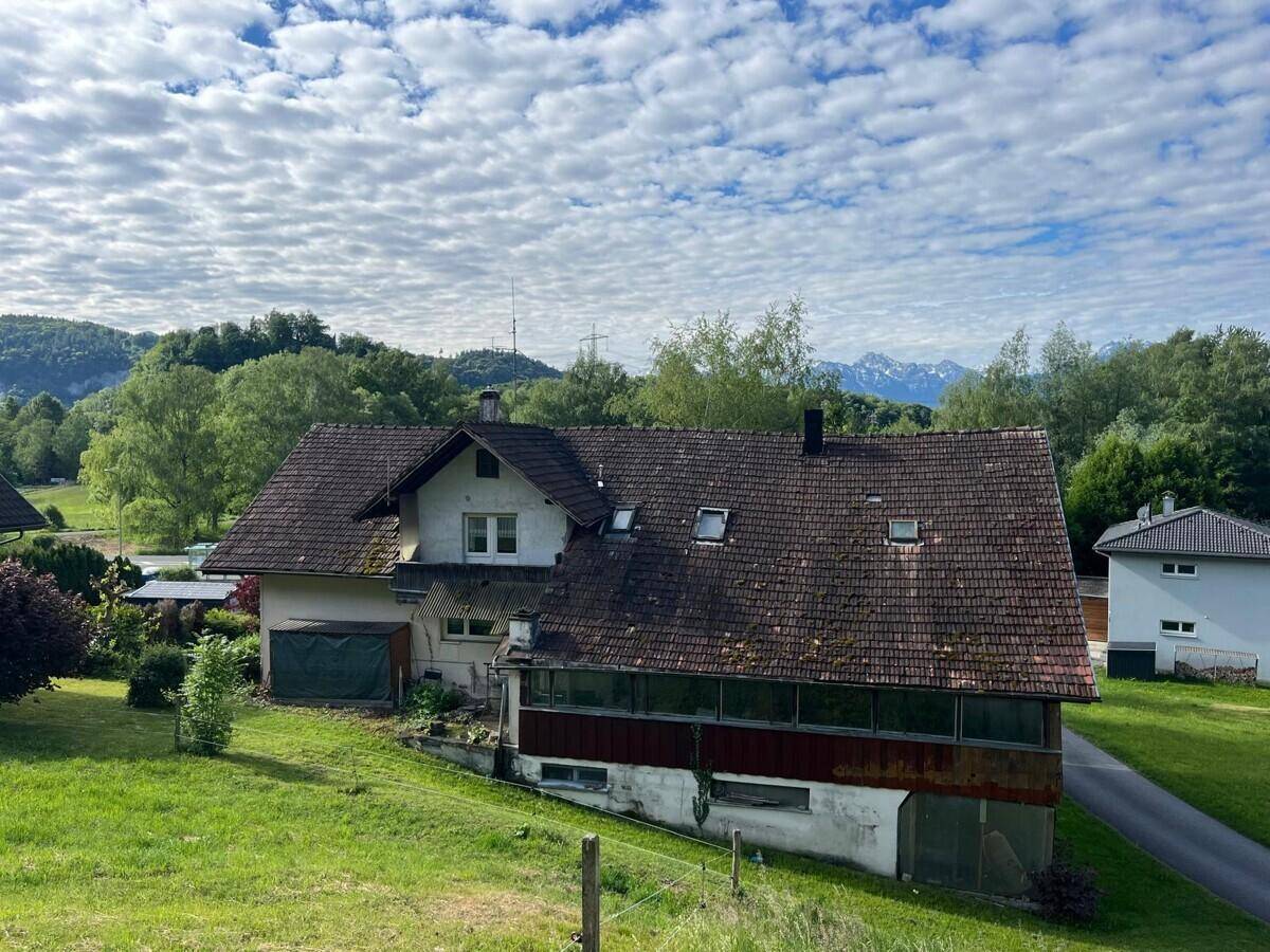 Vogelperspektive des Hauses mit Satteldach, umgeben von weitläufigen Grünflächen und Bergpanorama.