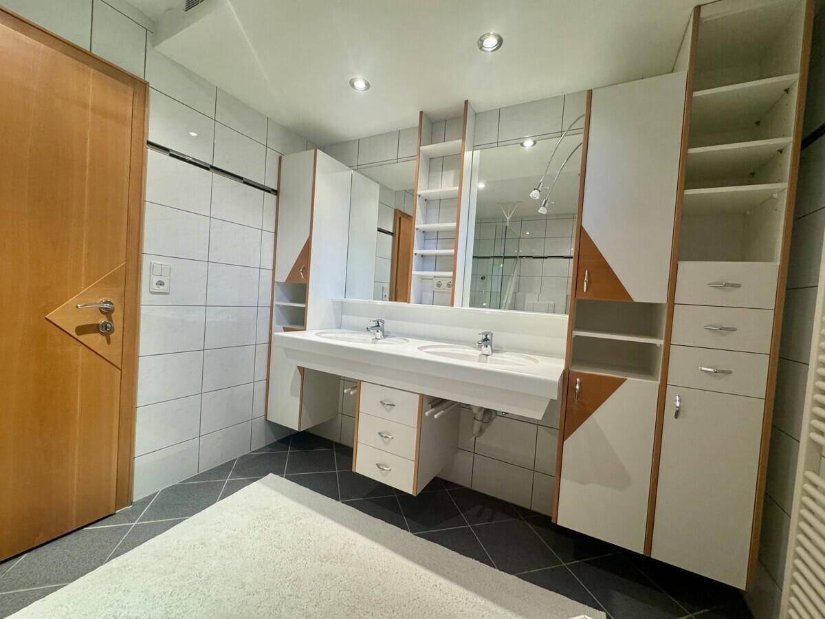 Modernes Badezimmer mit Doppelwaschbecken, großen Spiegeln und viel Stauraum.