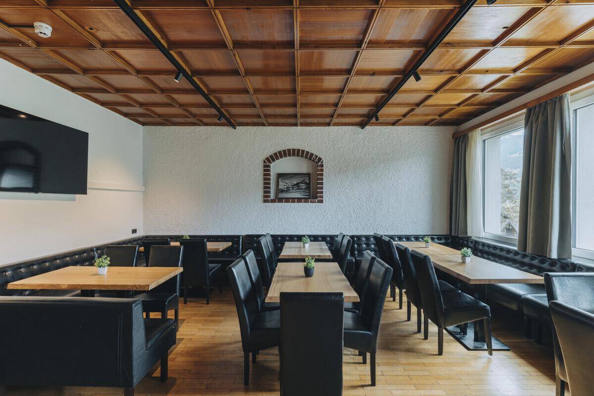 Traditioneller Speisebereich mit einer Kassettendecke aus Holz, Holzboden und bequemen Sitzbänken, ideal für größere Gruppen.