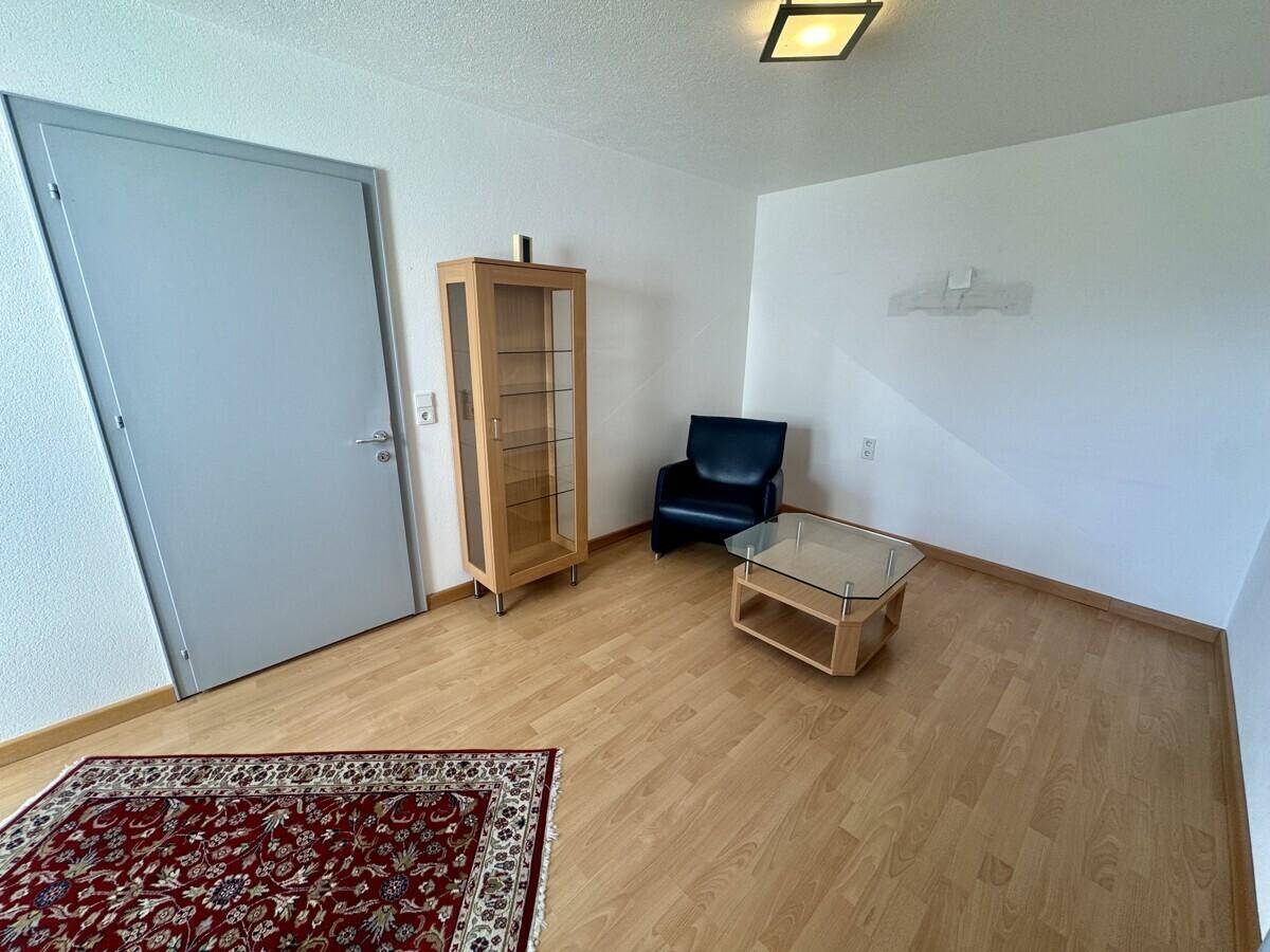 Wohnbereich mit Holzboden, Teppich und Vitrine, bietet eine gemütliche Atmosphäre.