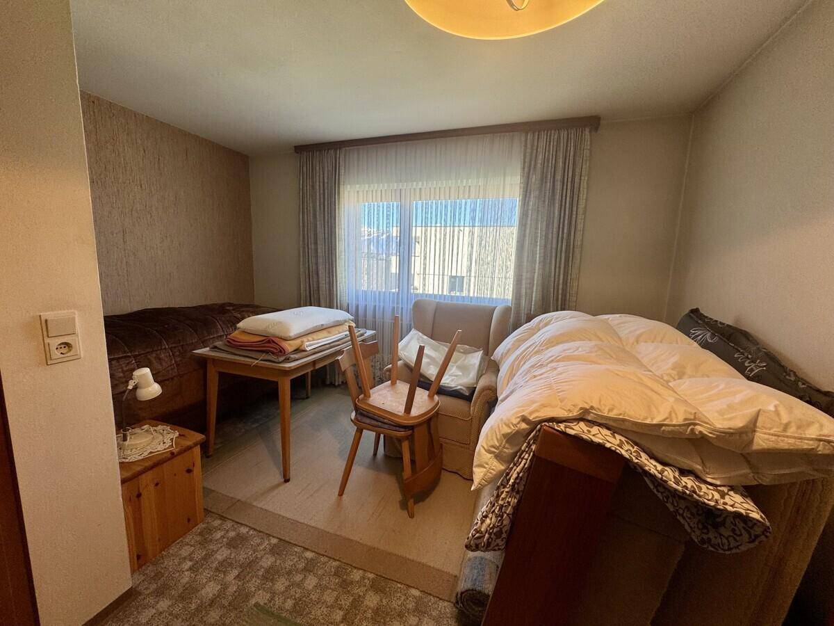 Schlafzimmer oder Gästezimmer mit Bett, Tisch und Sessel, mit Teppichboden.
