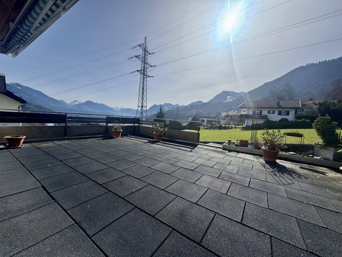 Große geflieste Terrasse mit Bergblick und viel Sonnenschein, ideal zum Entspannen.