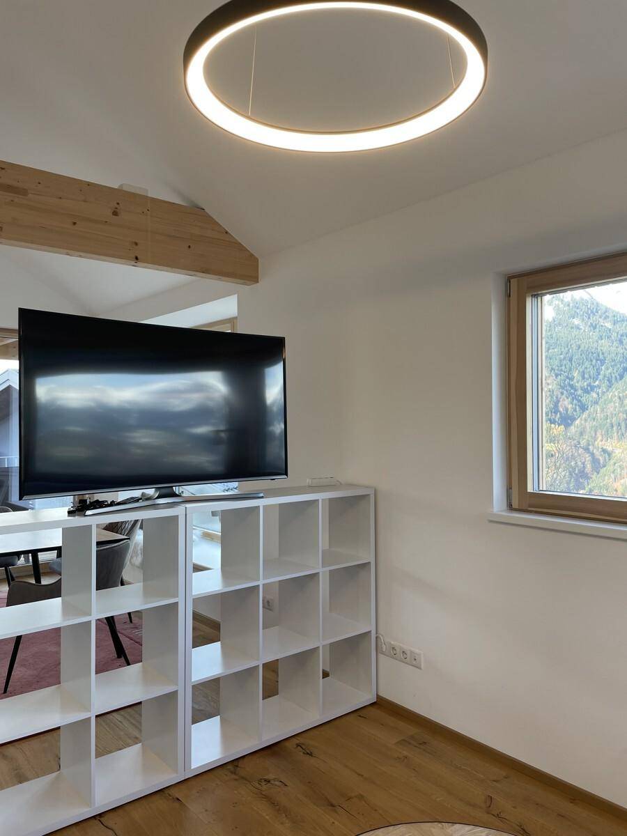 Wohnzimmer mit Fernseher auf einem Regal und Blick auf die umliegende Landschaft.