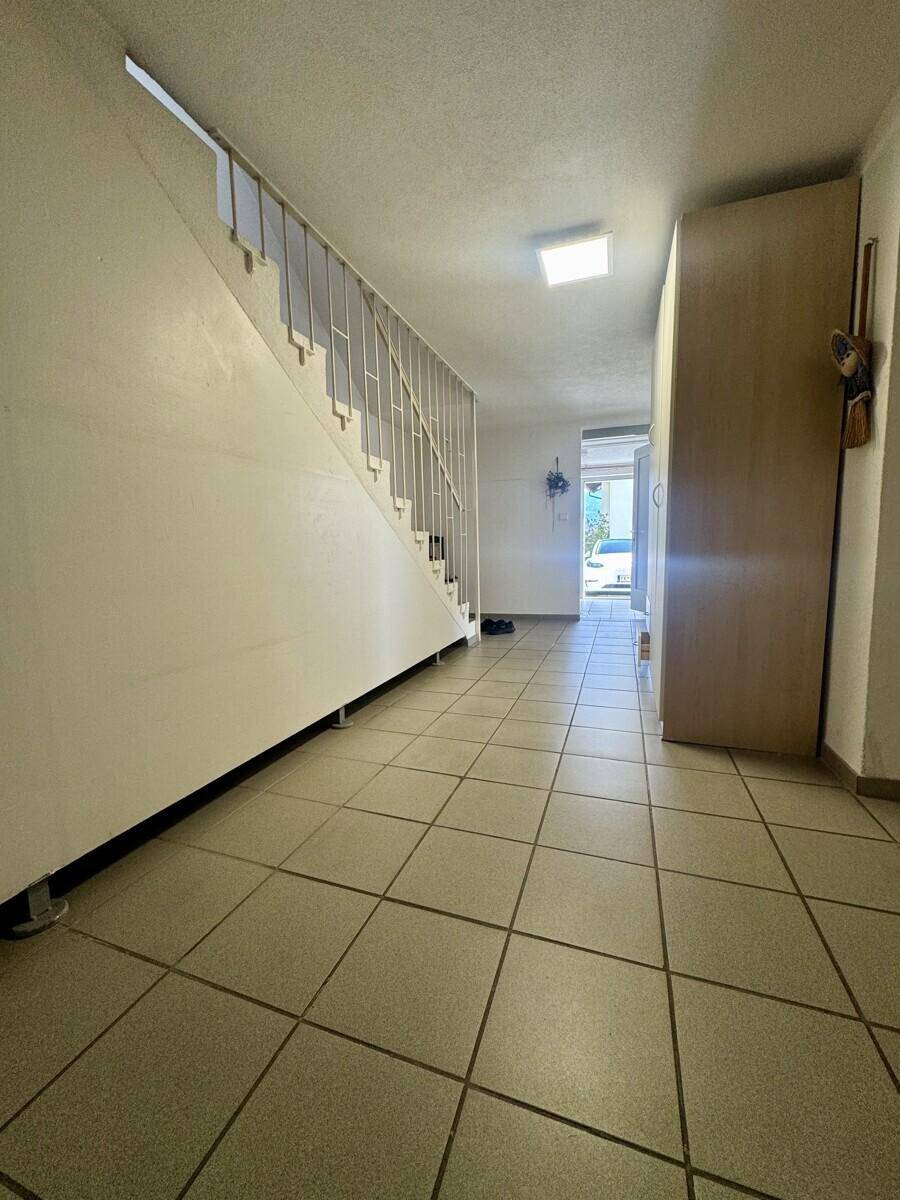 Eingangsbereich mit gefliestem Boden und Treppe, die in die oberen Stockwerke führt.