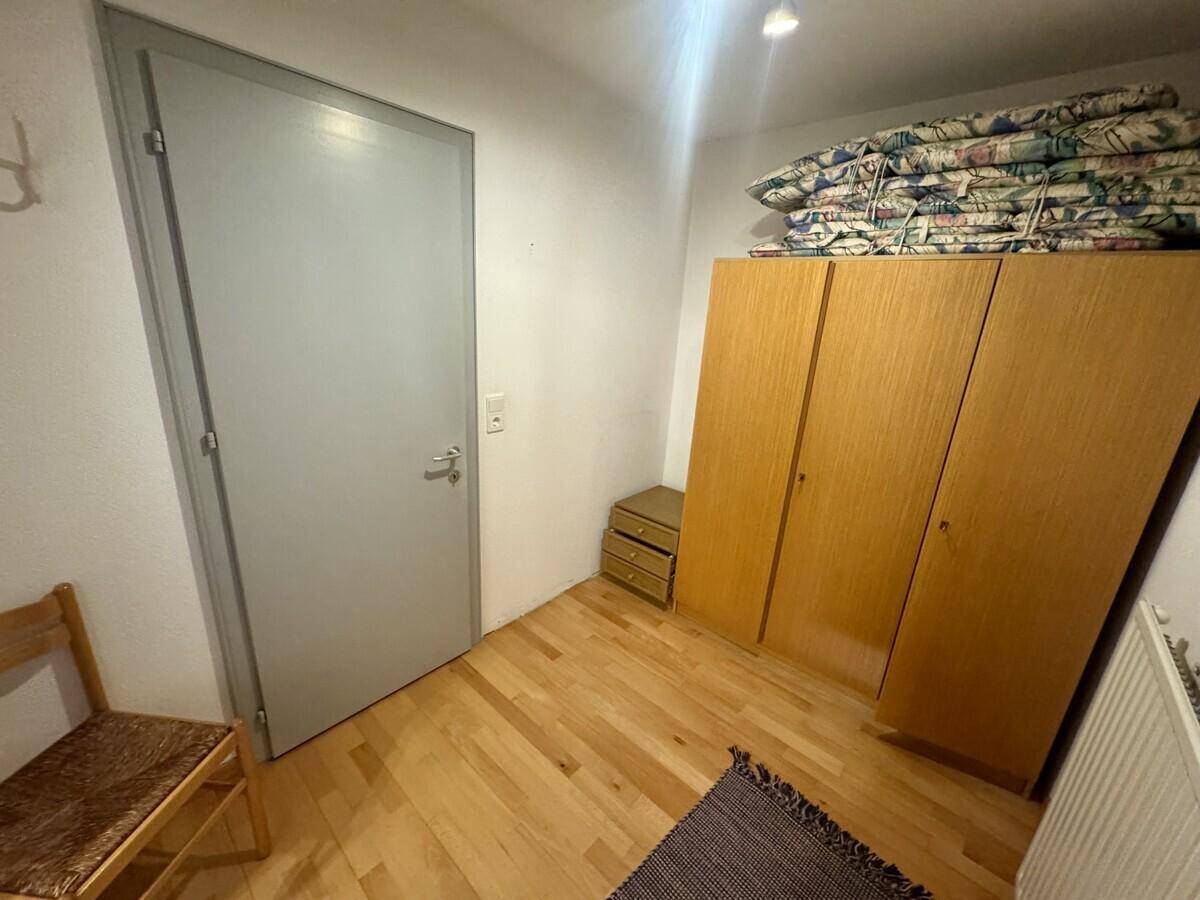 Zimmer mit Holzboden und Kleiderschrank, bietet zusätzlichen Stauraum.