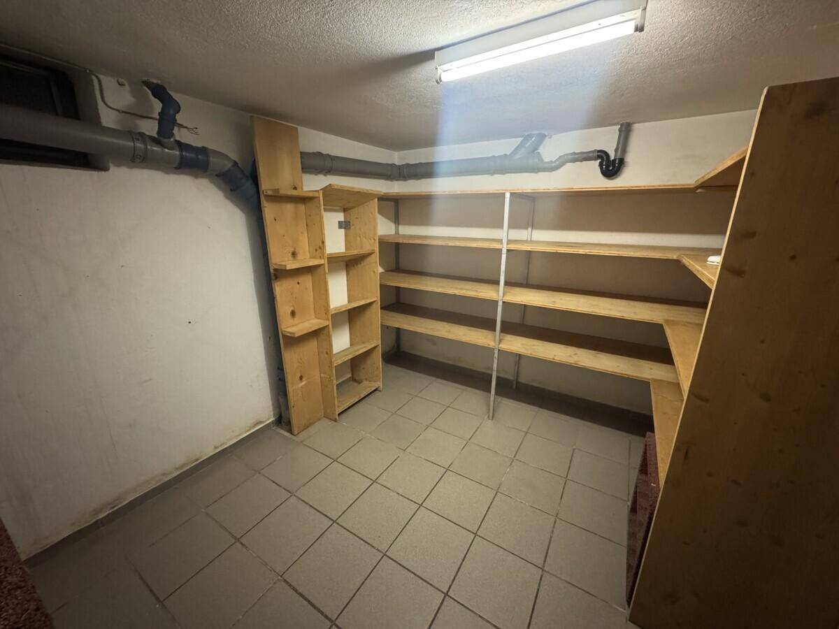 Kellerraum mit Holzregalen und gefliestem Boden, ideal für zusätzliche Lagerung.