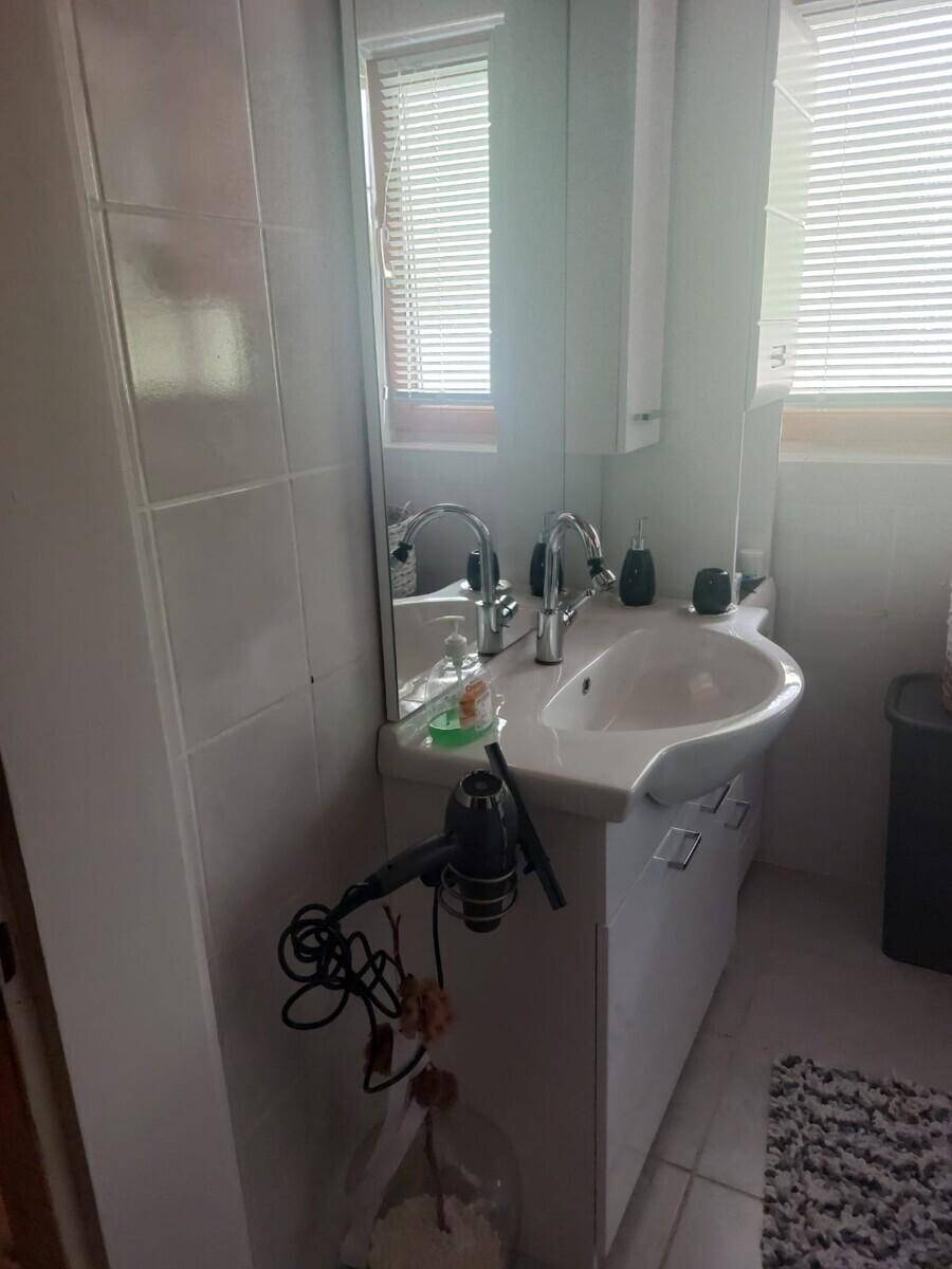 Badezimmer mit Waschbecken, Spiegelschrank und einem Fenster, das natürliches Licht hereinlässt.