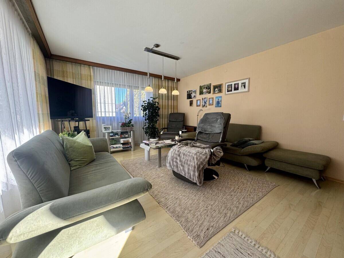 Gemütliches Wohnzimmer mit bequemen Sofas, Fernseher und hellem Laminatboden.