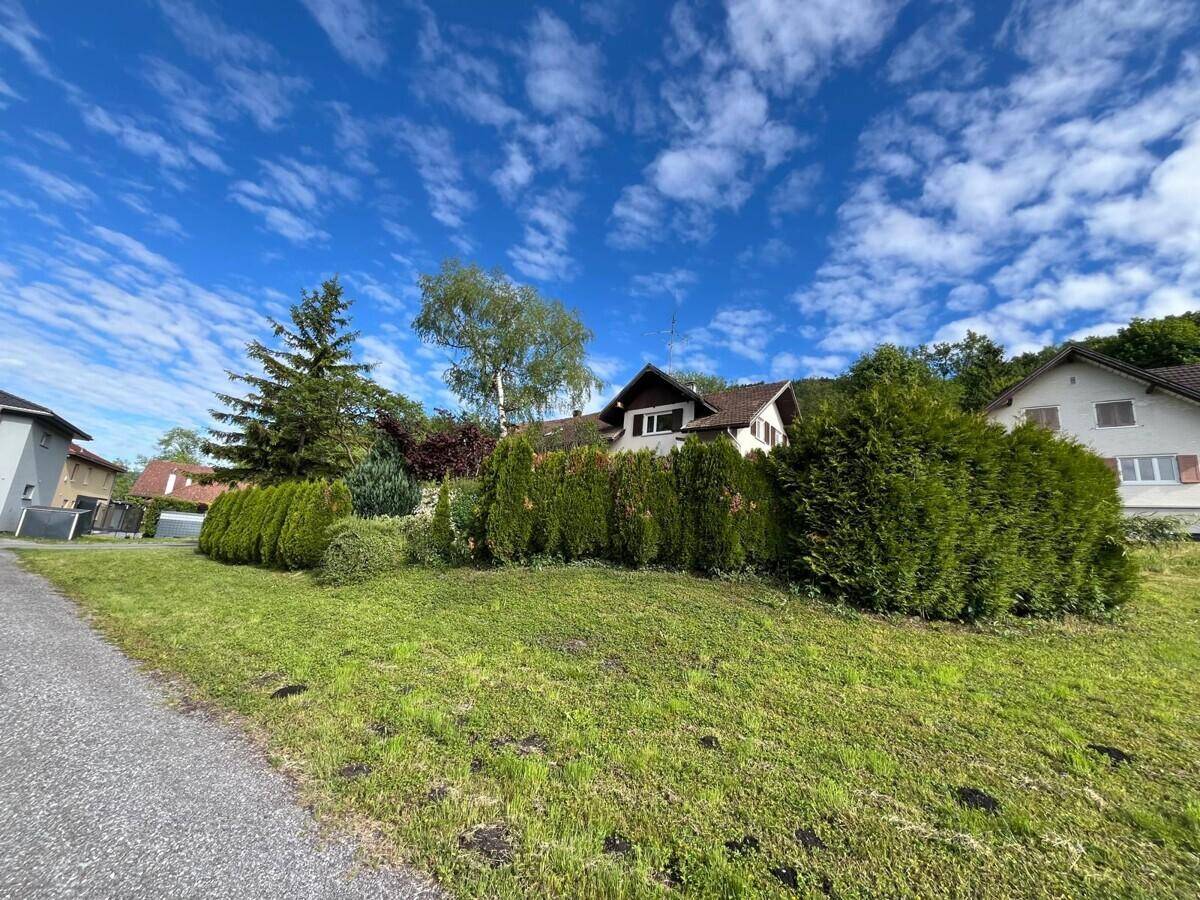 Das Haus ist teilweise von einer hohen Hecke umgeben, mit Zufahrt und weitläufigem Rasenbereich.